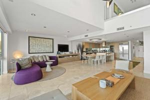 un salon avec un canapé violet et une table dans l'établissement Beachfront - Panoramic View 4BR Penthouse - PH4, à Palm-Eagle Beach