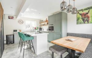 a kitchen with a wooden table and green cabinets at April Cottage in Bacton