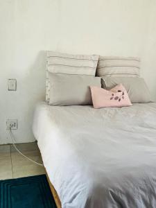 a white bed with a pink pillow on it at The Ripanga Nest in Nelspruit
