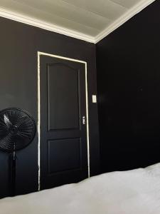 a bedroom with a black door and a fan at The Ripanga Nest in Nelspruit