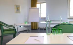 stół z 2 zielonymi krzesłami i szklaną butelką w obiekcie Hotel Walserwirt w mieście Wals-Siezenheim +37 zdjęć