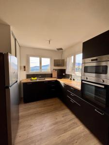 a kitchen with black cabinets and stainless steel appliances at Villa de Montchamp in Chambonas +4 photos