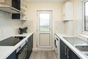 a white kitchen with a sink and a dishwasher at The Cozy Two beds, FREE parking, SKY in Bedford