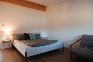 a bedroom with a bed and a chair in it at Hohenzollern Wellness Loft mit Panorama Sauna in Burladingen