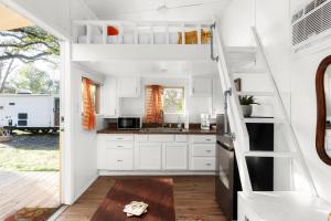 奥斯汀Cozy Tiny Home on an Eco Farm的一间厨房,厨房内有白色的橱柜和一个小房子里的楼梯