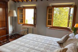 サン・カシャーノ・イン・ヴァル・ディ・ペーザにあるSuite Luce at Villa Santa Lucia Nuovaのベッドと2つの窓がある寝室