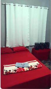 Habitación con cama roja con colcha roja y colcha amarilla. en Quintal Compartilhado - Casa Temporada, en Armacao dos Buzios