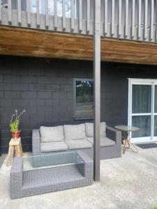 a wicker couch sitting on the patio of a house at Beach across the road in Waihi Beach