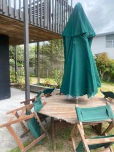 a picnic table with a green umbrella and chairs at Beach across the road in Waihi Beach +11 photos