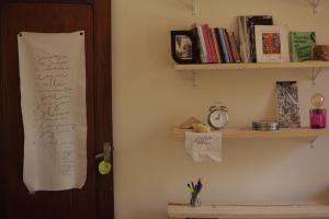 a room with a wall with a shelf with books at Quarto Casal com Varanda Casa Caramel in Belo Horizonte