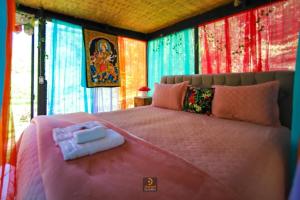 a bedroom with a large pink bed with colorful curtains at Nirvana Glamping, Nature Glass Chalet in São Francisco Xavier
