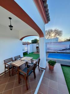 a patio with wooden tables and chairs and a swimming pool at Casa Moisés Atardecer in El Palmar
