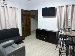 a living room with a couch and a tv and a table at Schultz Apartamento in Alajuela
