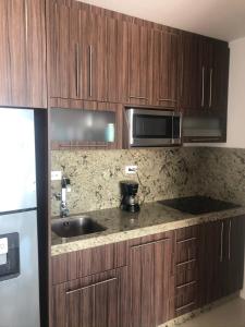 a kitchen with wooden cabinets and a sink and a microwave at Punta Centinela in Punta Blanca