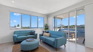Una sala de estar con dos sillas azules y una mesa. en Boronia Beach House One, en Sawtell
