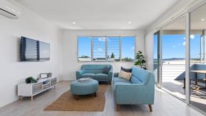 Una sala de estar con dos sillas azules y un televisor. en Boronia Beach House One, en Sawtell