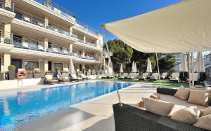 a hotel swimming pool with chairs and a white umbrella at Vincci Selección Aleysa in Benalmádena