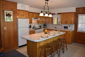 a kitchen with wooden cabinets and a island with bar stools at Sequoia House at The Redwoods in Wawona