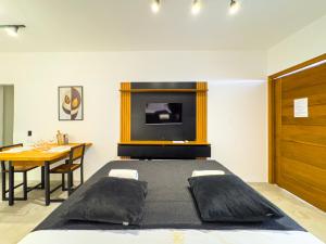 a bedroom with a bed and a table and a television at Pousada Praia do Carioca Búzios in Búzios