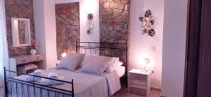 a bedroom with a bed and a stone wall at Elia Village by Irida Iris Group - Superior Vila in Plomarion