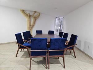 ein Esszimmer mit einem Tisch und blauen Stühlen in der Unterkunft Casa El Mirador - Burgos, Familiar in Temixco