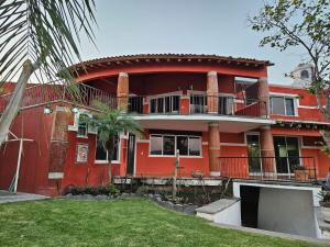 ein rotes Haus mit einem Balkon und einem Hof in der Unterkunft Casa El Mirador - Burgos, Familiar in Temixco