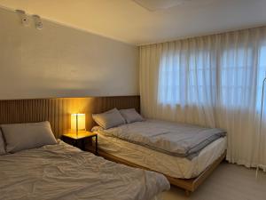 a hotel room with two beds and a window at Pachira House in Seoul