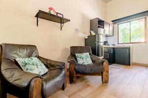 a living room with two leather chairs and a kitchen at Villa Jr 3 near the peñon guacalillo in Tarcoles