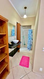 a bathroom with a sink and a shower with a pink rug at Na Boca do Jacaré in Caraguatatuba
