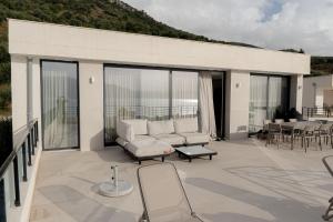 a patio with a couch and chairs on a balcony at Crystal Beach Radhime in Vlorë
