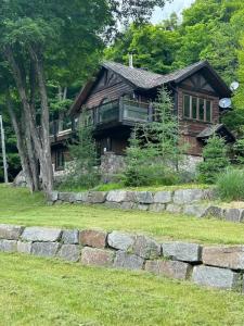 a wooden house with a stone wall in front of it at Lake views, spa, king bed, Golf Club amenities in Mont-Blanc