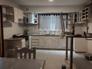 a kitchen with white cabinets and a table and a window at Casa cerca de la playa in Mar del Plata