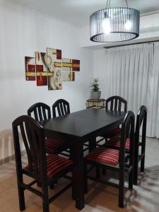 a black dining room table with chairs and aandelier at Casa cerca de la playa in Mar del Plata