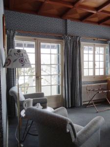 sala de estar con sillas, lámpara y ventanas en Auberge Des Chasseurs, en Échenevex