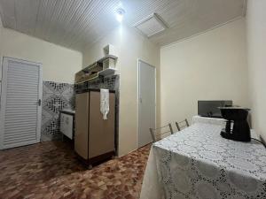 a kitchen with a table and a refrigerator in a room at Apê Estação do Sorriso in Bananal
