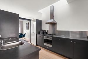 une cuisine avec des comptoirs noirs, un évier et une cuisinière dans l'établissement South Yarra Luxe - Spacious Townhouse & Parking, à Melbourne 7 autres photos