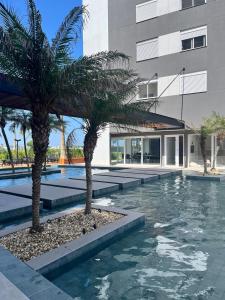 a pool with two palm trees in front of a building at Apartamento alto padrão in Xangri-lá