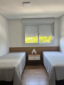 two beds sitting in a room with a window at Apartamento alto padrão in Xangri-lá +15 photos