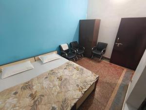 a bedroom with a bed and two chairs at Shree Dhaam Homestay in Faizābād