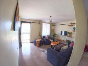 a living room with blue couches and a tv at Savannah Suites Gilgil in Gilgil