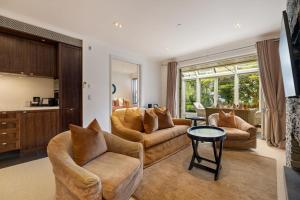 ein Wohnzimmer mit zwei Sofas und einem Tisch in der Unterkunft Craigroy 1 Lakeshore apartment with conservatory in Queenstown