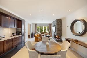 a kitchen and living room with a wooden table and chairs at Craigroy 2 Lakeshore apartment with conservatory in Queenstown