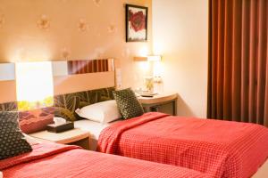 a hotel room with two beds and a table at Hotel Dewarna Sutoyo Malang in Malang