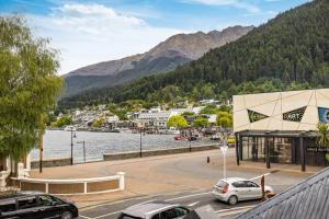 a street with cars parked in front of a body of water at Ben Lomond 1 Top Floor Lakeshore Apartment in Queenstown