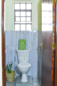 un baño con aseo y un letrero en la pared en Savannah Suites Gilgil, en Gilgil