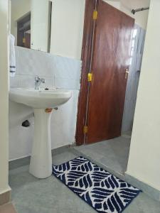 y baño con lavabo, espejo y alfombra. en Savannah Suites Gilgil, en Gilgil 43 fotos más