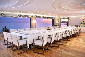 un lungo tavolo con tavoli e sedie bianchi in una stanza con vista sull'oceano di Vincci Selección Aleysa a Benalmádena