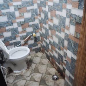 a bathroom with a toilet and a tiled wall at Gaurangi dham in Mathura