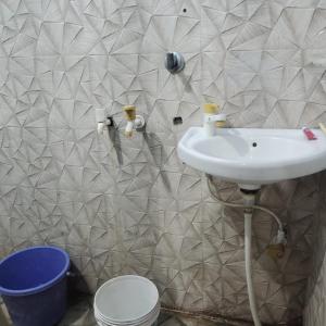 a bathroom with a sink and a tiled wall at Gaurangi dham in Mathura +2 photos