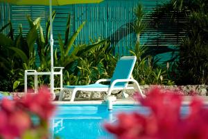 two chairs and an umbrella next to a swimming pool at Hotel Cap Sud Caraibes in Le Gosier